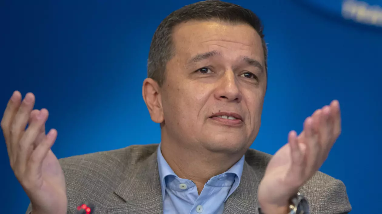 În imagine este ilustrat Sorin Grindeanu, îmbrăcat în costum gri și cămașă albastră