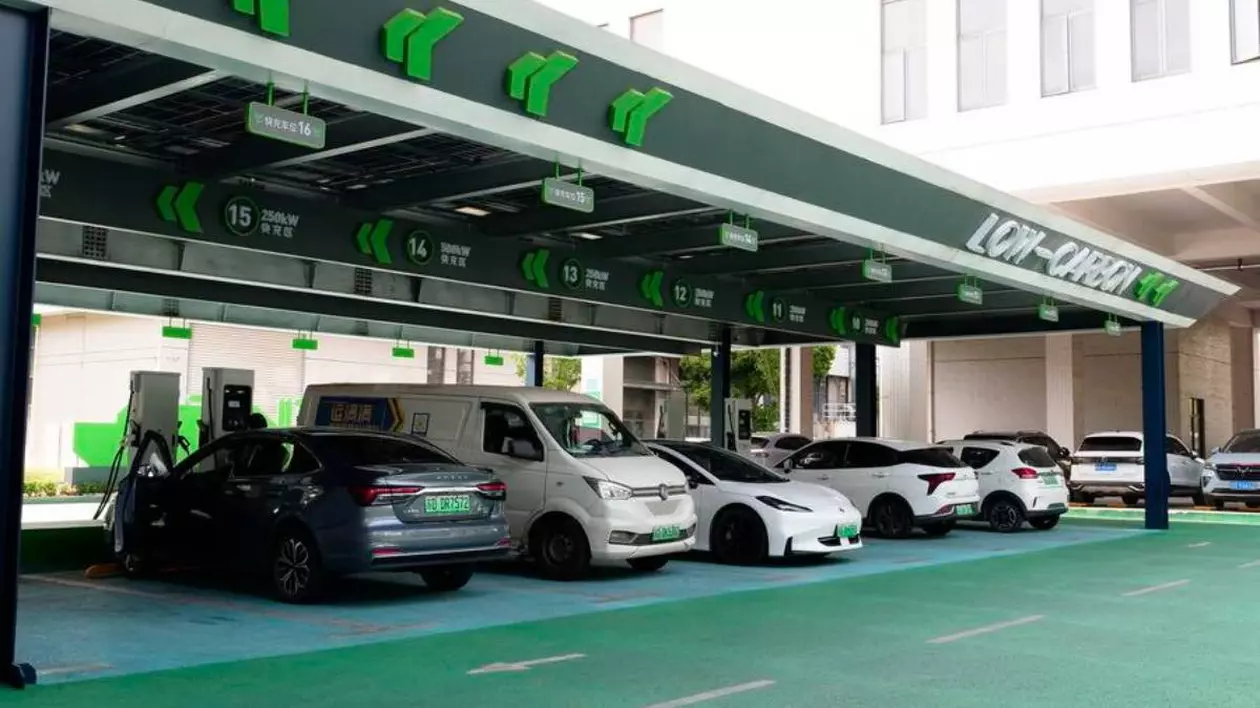 Stație de încărcare pentru mașini electrice din China. În stație sunt conectate mai multe mașini electrice, o dubă albă, un model Tesla S si alte mașini.