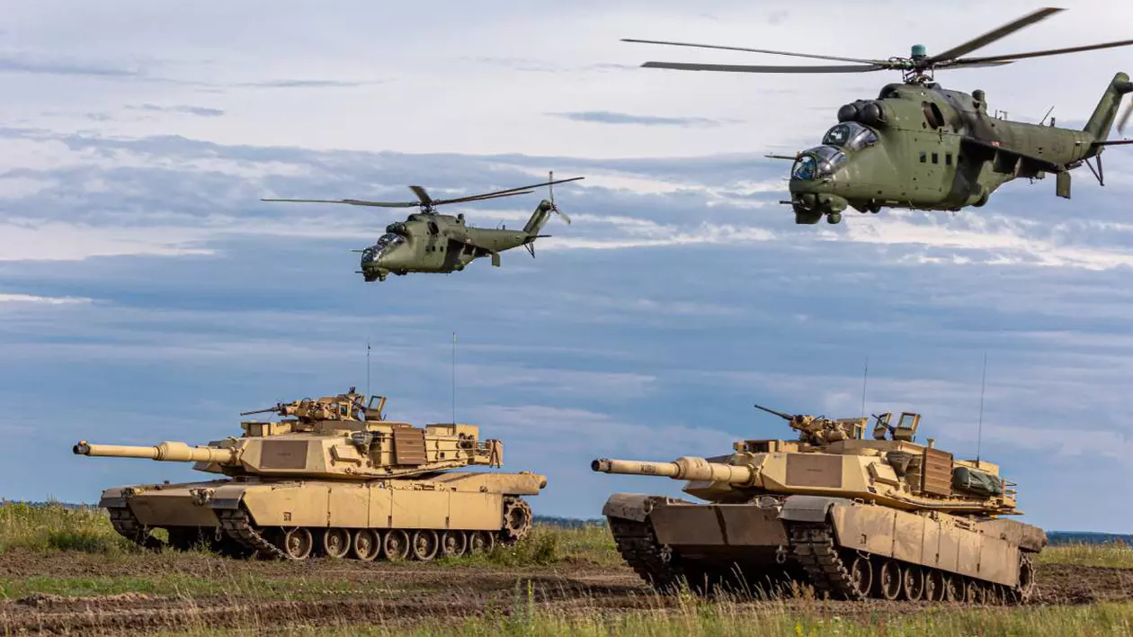 Tancuri Abrams pe un teren de luptă și elicoptere militare.