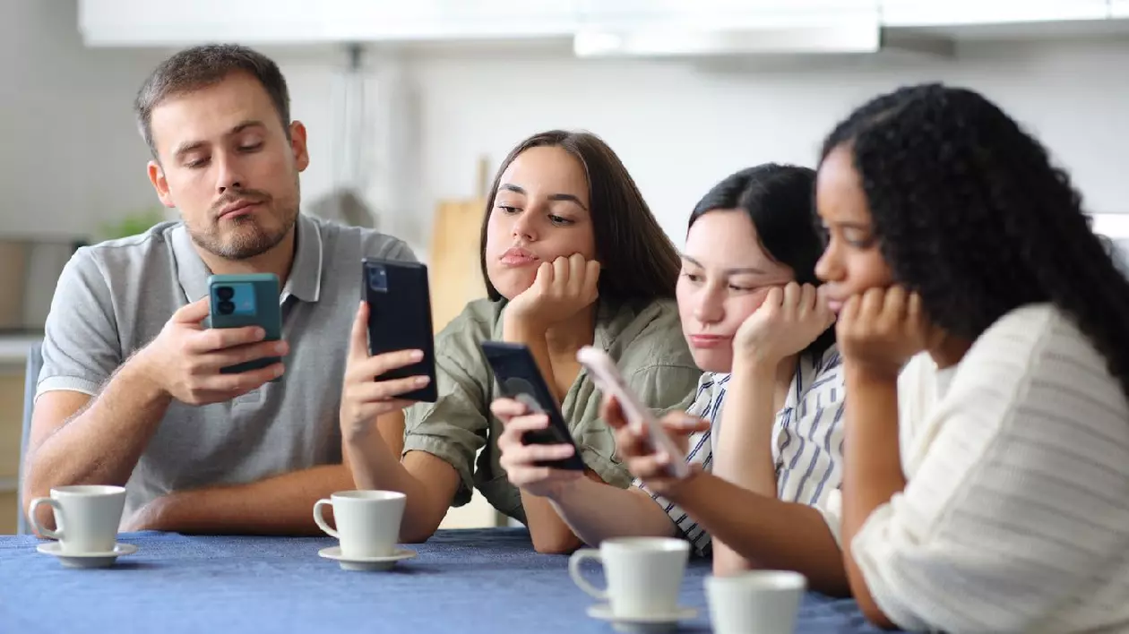 Prietenii plictisiți își folosesc telefoanele inteligente în bucătăria de acasă