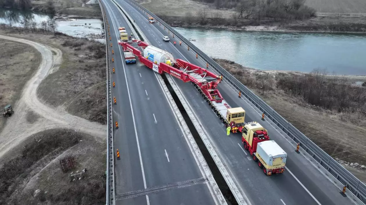 Transport agabaritic pe o autostradă, desfășurat pe un pod.Transportul se desfășoară pe diagonală, ocupând ambele sensuri ale autostrăzii