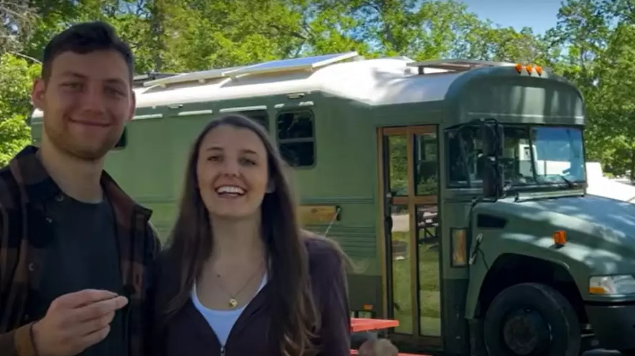 În imagine sunt ilustrați doi tineri, iar în spate este un autobuz de culoare verde, într-o curte