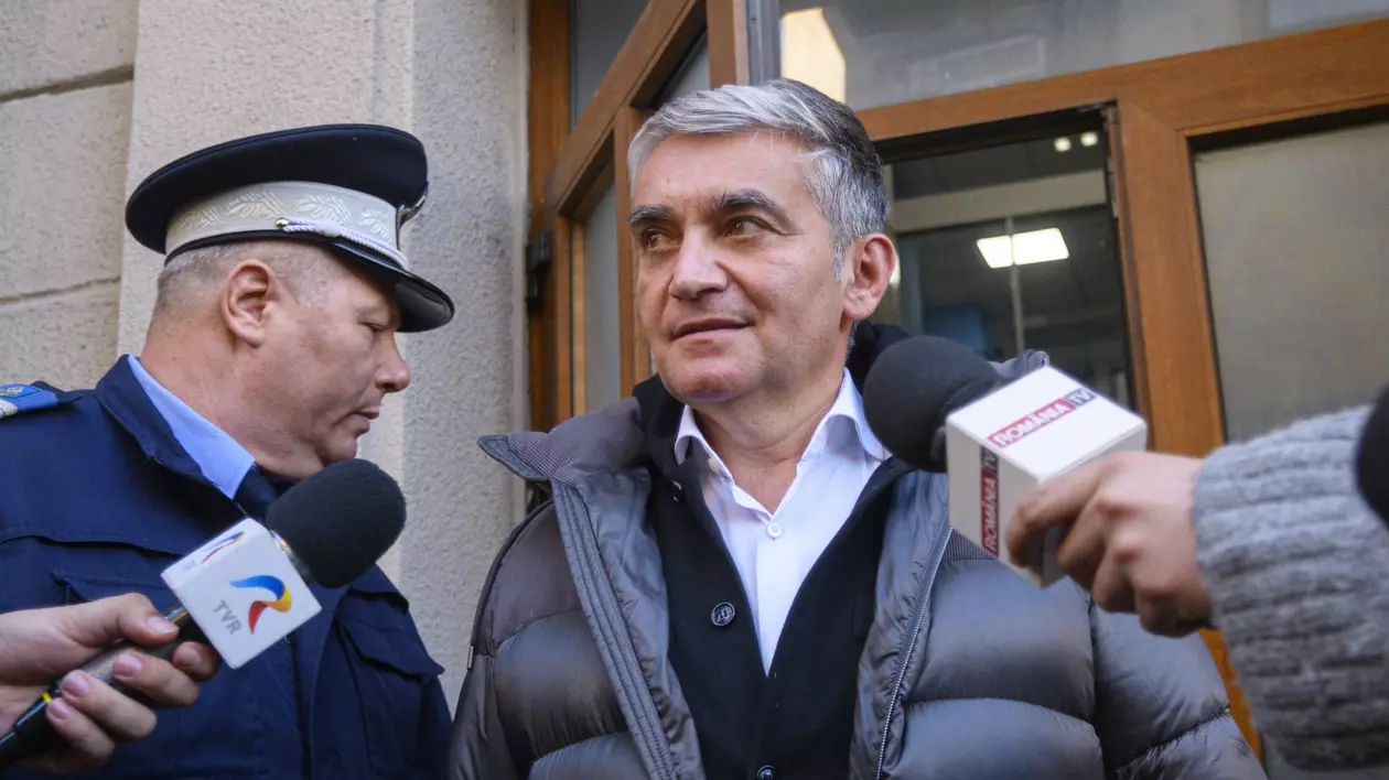 Vlad Oprea surprins în timp ce pleacă de la sediul DNA, pe 28 ianuarie 2024. În stânga e un polițist, iar primarul din Sinaia are în față două microfoane
