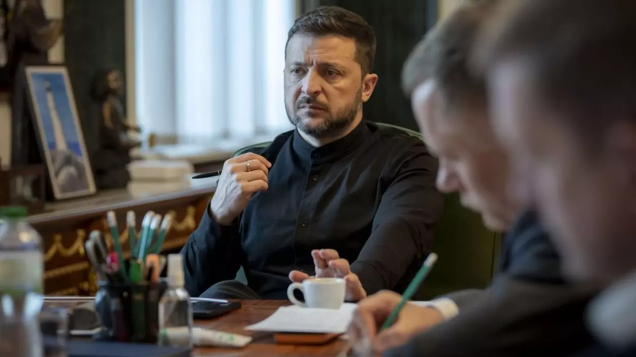Președintele ucrainean Volodimir Zelenski, îmbrăcat în negru, la birou, alături de câțiva consilieri care scriu