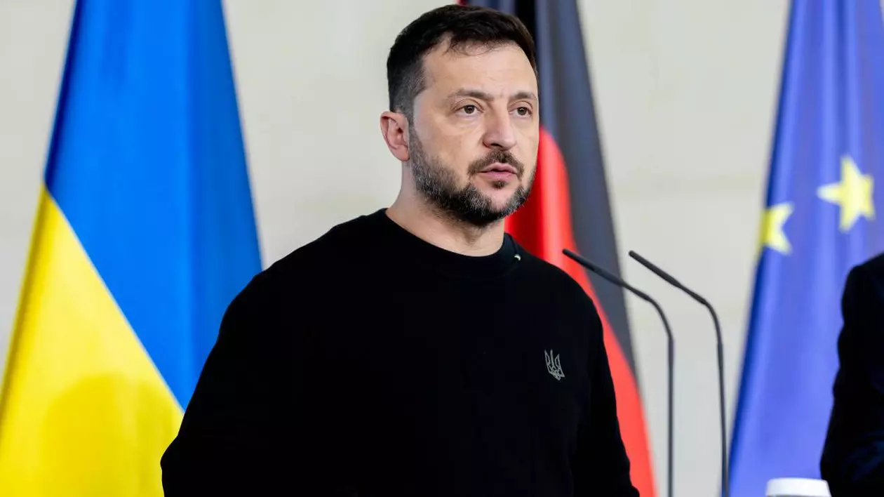 Volodimir Zelenski, îmbrăcat în negru, ține un discurs, iar în spatele său este așezat steagul Ucrainei și steagul Uniunii Europene.