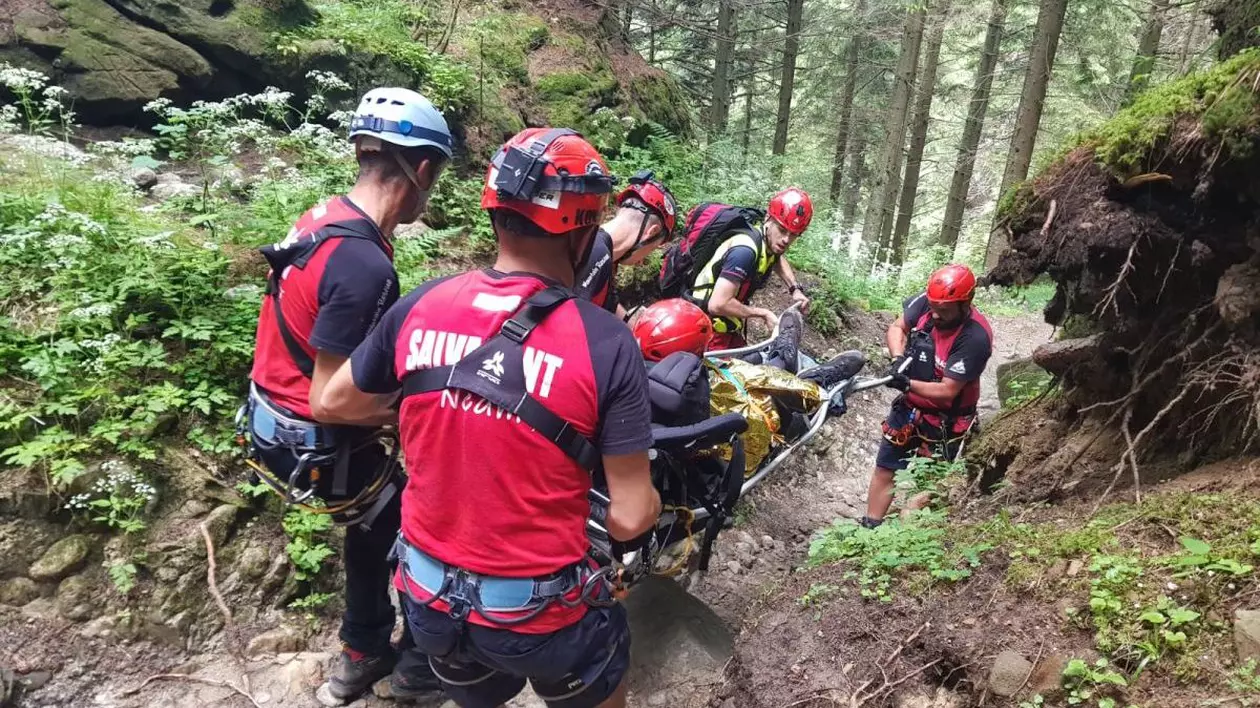 Salvamontiștii coboar de pe munte cu o targă pe care se află o persoană rănită