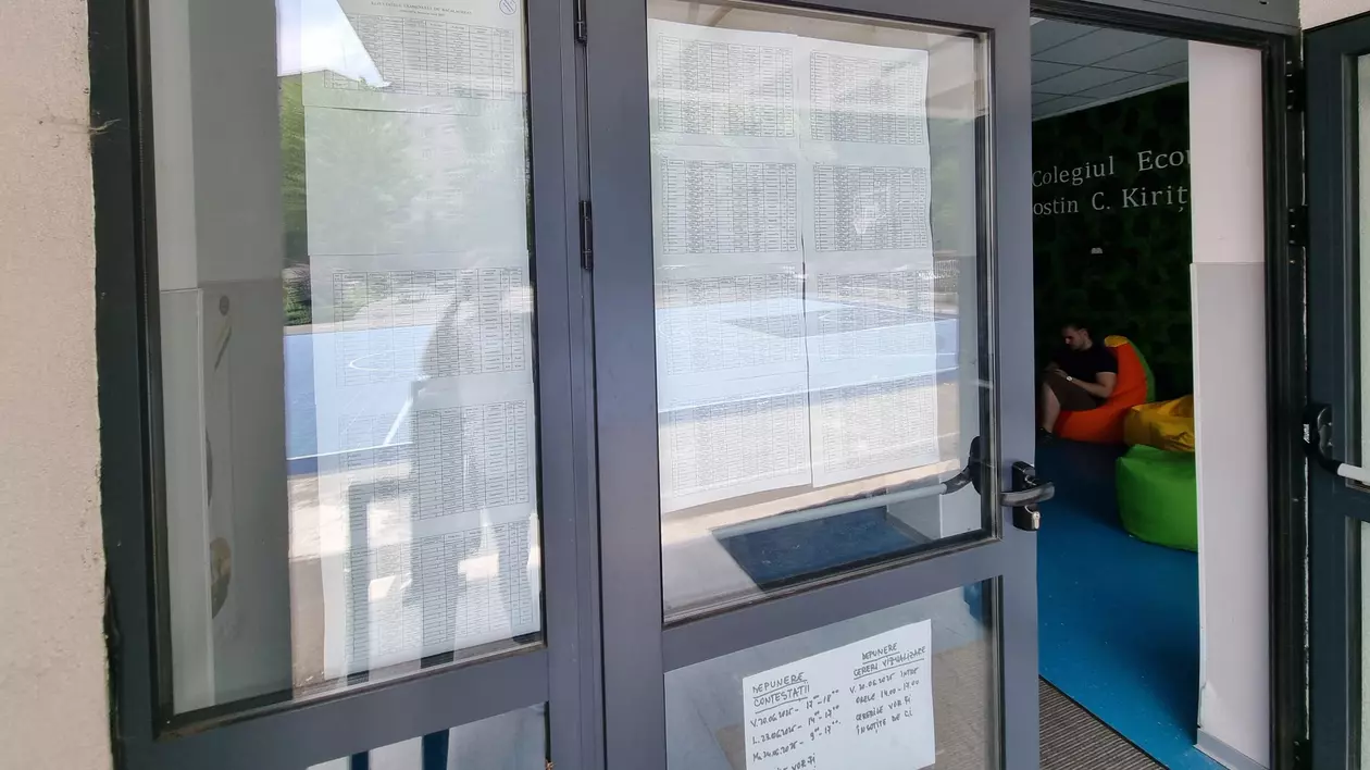un panou de sticla de la o scoala cu foi lipite. este vorba de afisarea rezultatelor la bacalaureat 2025