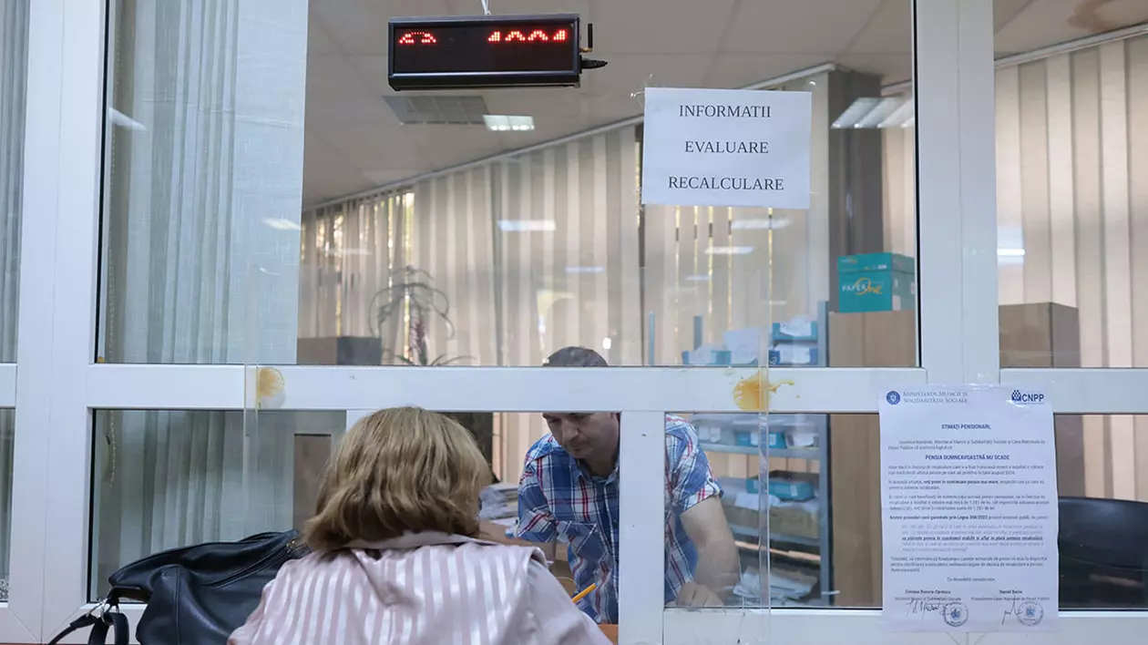 O femeie stă la ghișeu să obțină informații de la angajatul instituției