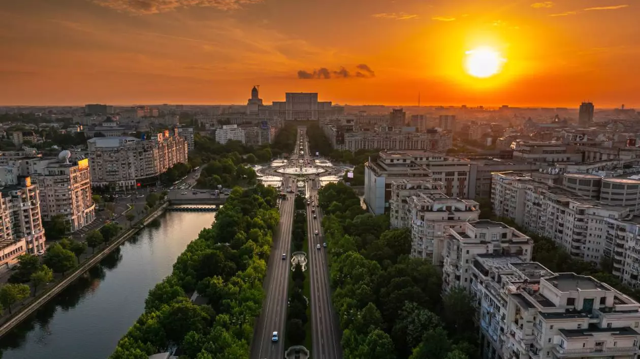 Apus de soare în București, peste Palatul Parlamentului, cerul este portocaliu.