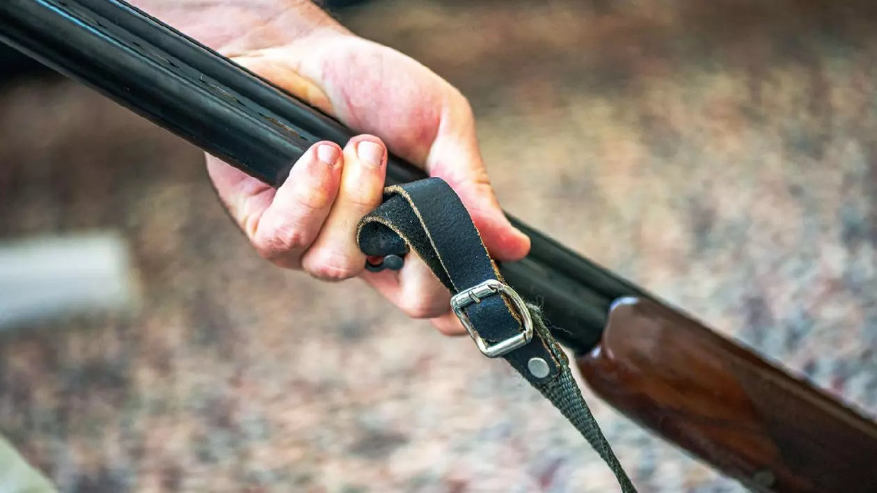 Un bărbat curăță meticulos o pușcă veche folosind ulei și gadgeturi de curățare, prezentând atenția la detalii și măiestria armelor de foc de epocă.