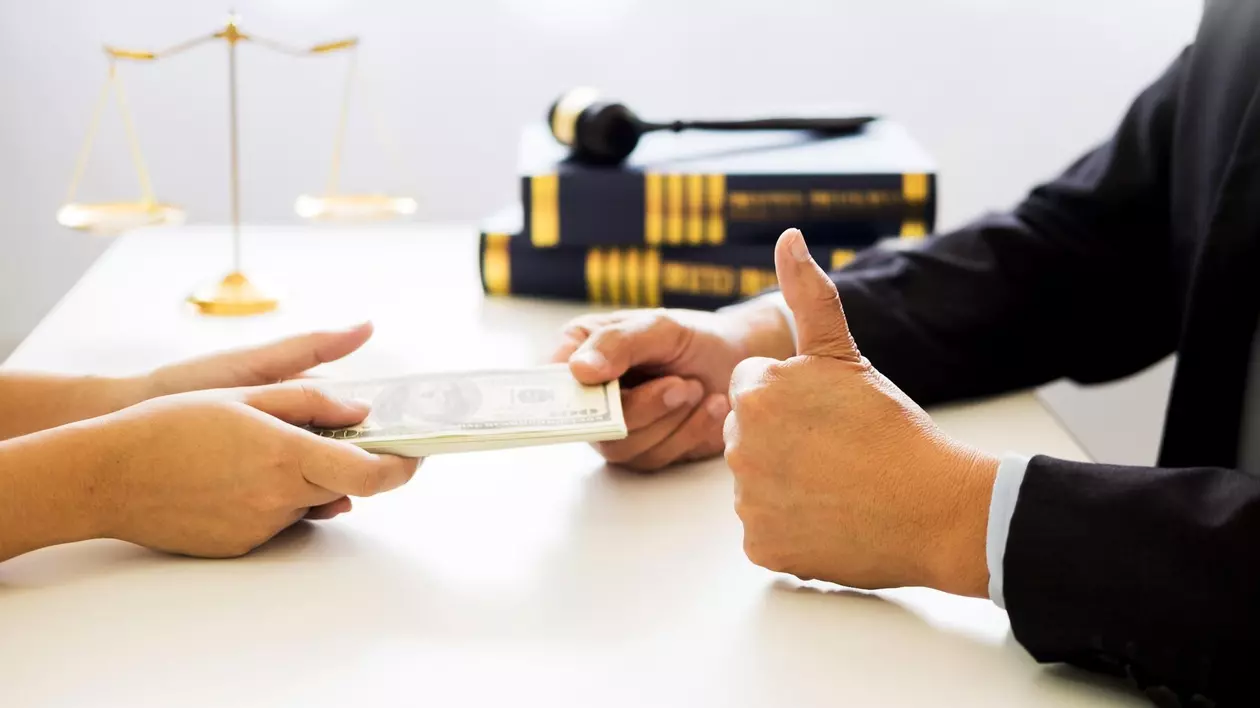 Poză cu un avocat (dreapta) care primește bani de la un client (stânga)
