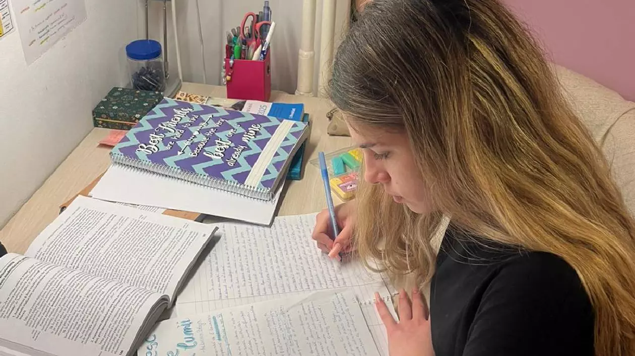 Tânără care scrie la birou un comentariu și învață pentru Bacalaureat