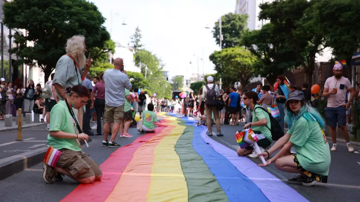 steag cu culorile cucubeului așezat pe asfalt în Piața Victoriei, locul unde se adună participanții marșului Bucharest Pride 2025