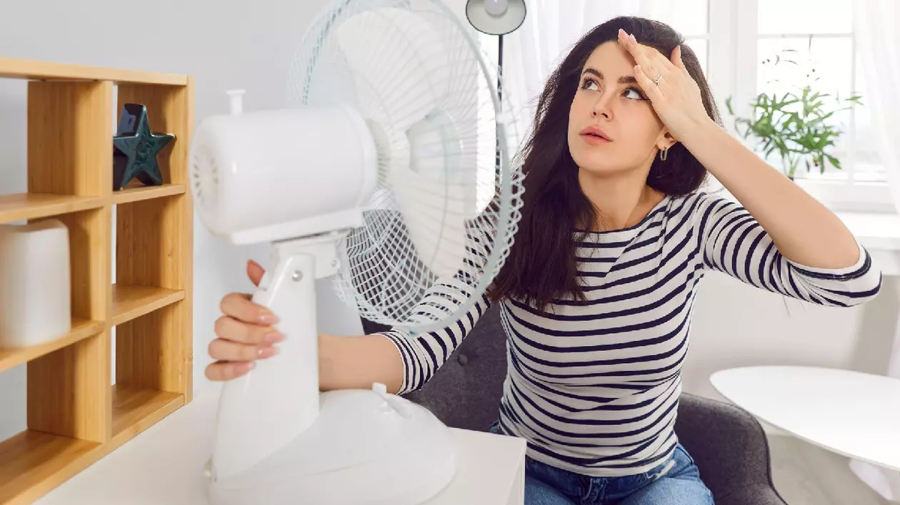 Femeie încercând să se răcorească cu un ventilator în timpul unei zile toride de vară