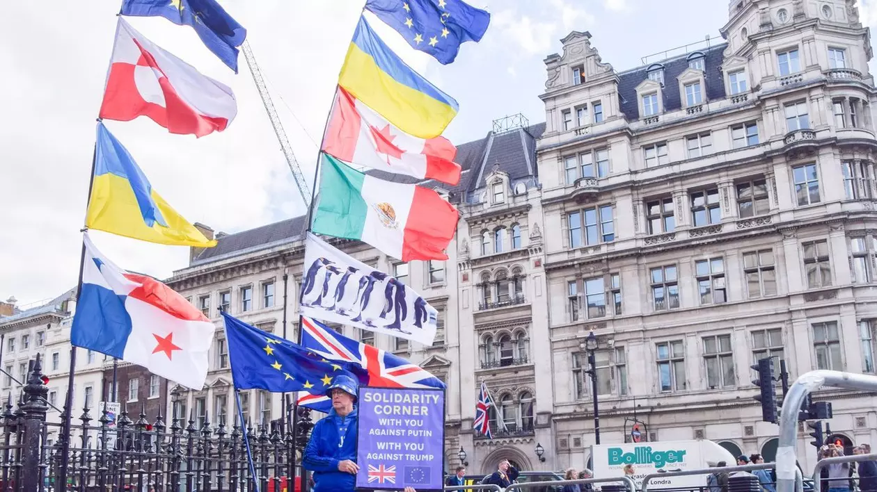 Un activist creează un „colț de solidaritate” anti-Trump și anti-Putin cu steaguri ale Canadei, UE, Ucrainei, Mexicului, Panama și pinguini în timpul unui protest în Piața Parlamentului. Protestatari în fața Parlamentului, Londra, Anglia, Regatul Unit - 07 mai 2025