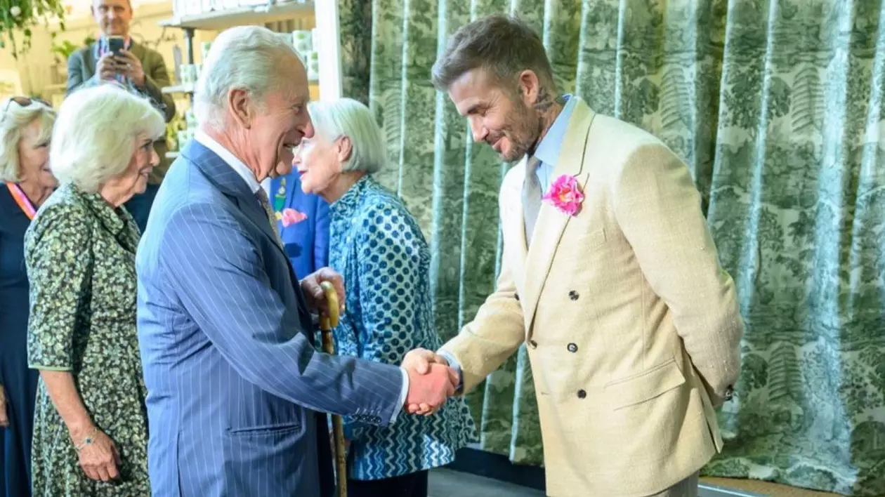 Regele Charles, in costum albastru, și Regina Camilla alături de el, s-au întâlnit cu David Beckham la magazinul Highgrove Estate, Beckham poartă un costum crem și un trandafir în piept si dă mâna cu Charles