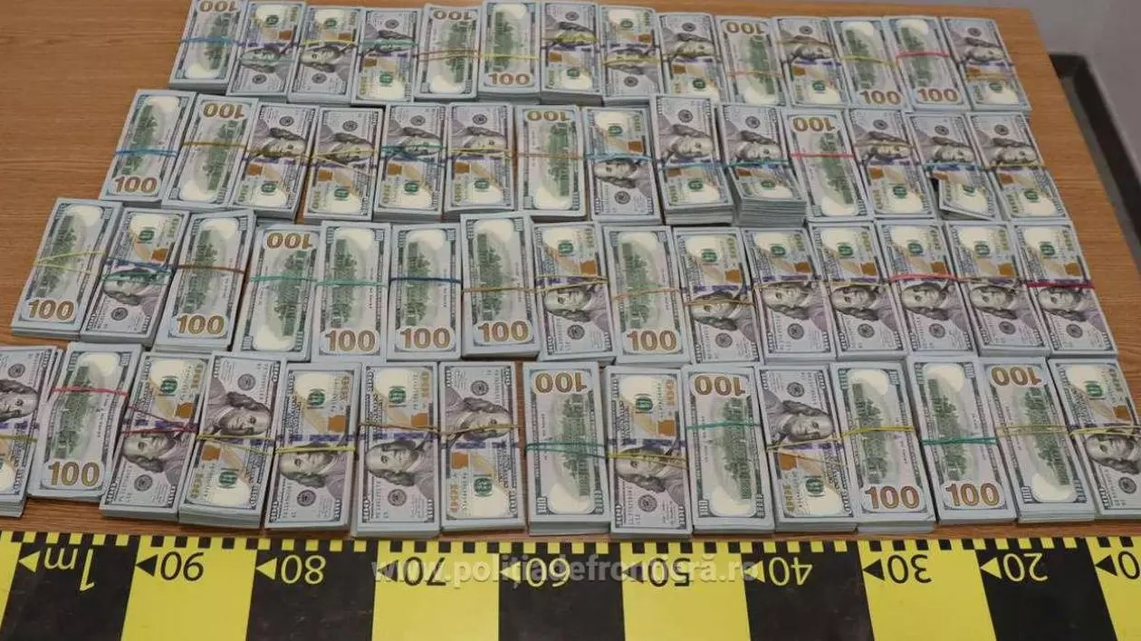 Imagine cu banii găsiți de polițiștii de frontieră în cartușele de țigări. Bancnotele sunt întinse pe o masă