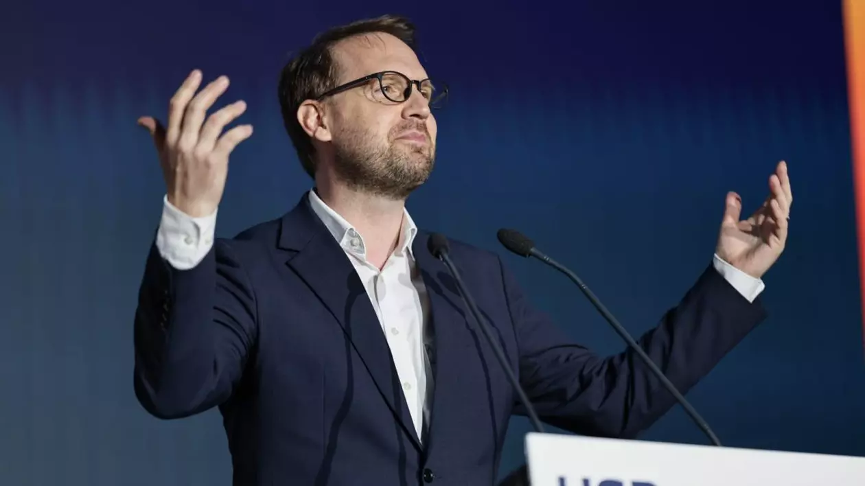 Dominic Fritz ridică mâinile în spatele pupitrului la congresul USR