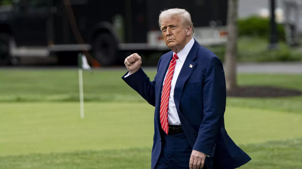 Donald Trump surprins în timp ce ține pumnul strâns. Poartă un costum albastru, cu cămașă albă și cravată roșie