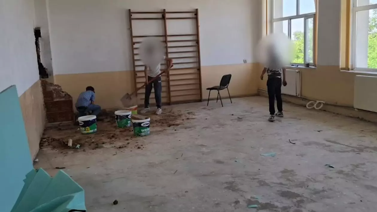 Doi elevi cu fețele blurate ajută la reperații în sala de sport a unei școli, iar un altul este cu spatele și lângă ei sunt găleți de materiale de construcții, în Dolj