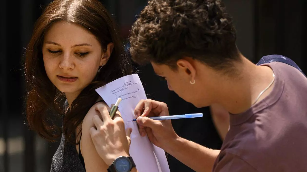 Un adolescent rezolvă o problemă de matematică ținând foaia de calcul pe spatele unei fete care se uită îngrijorată spre el
