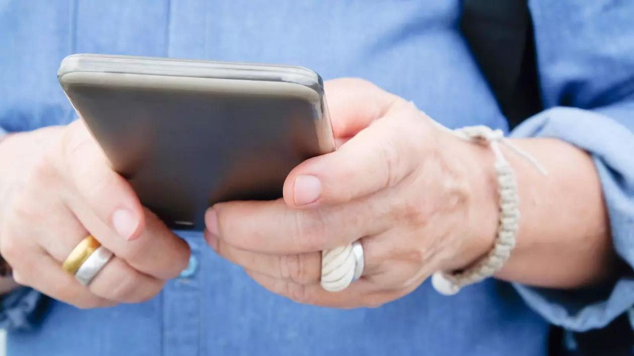 Imagine cu o femeie în vârstă care ține în mâini un telefon mobil