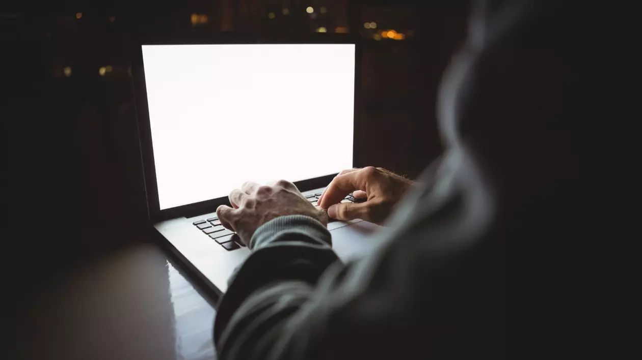 În imagine este ilustrat un bărbat care tastează pe un laptop