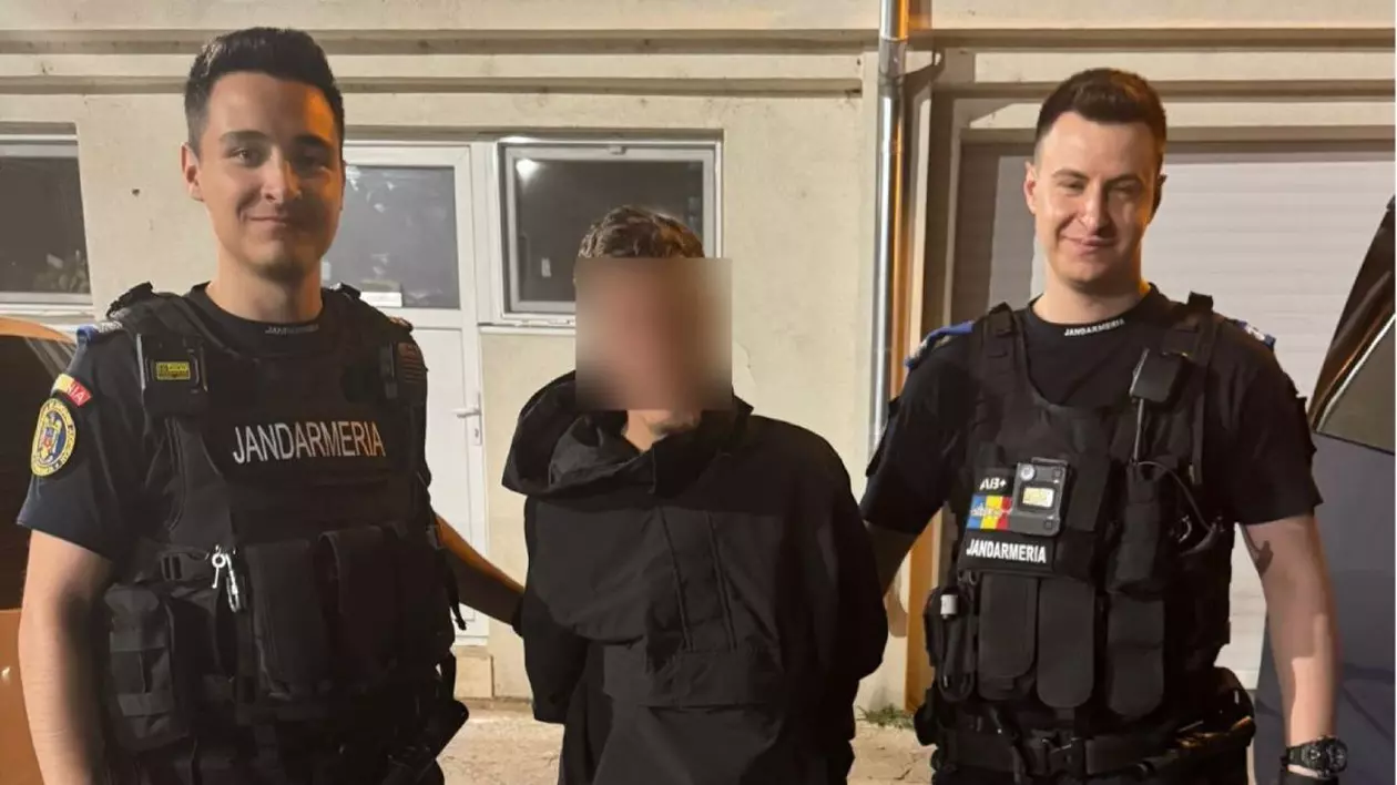 Doi jandarmi, îmbrăcați în uniforme, îl țin de mâini pe un suspect, îmbrăcat în negru și cu fața blurată