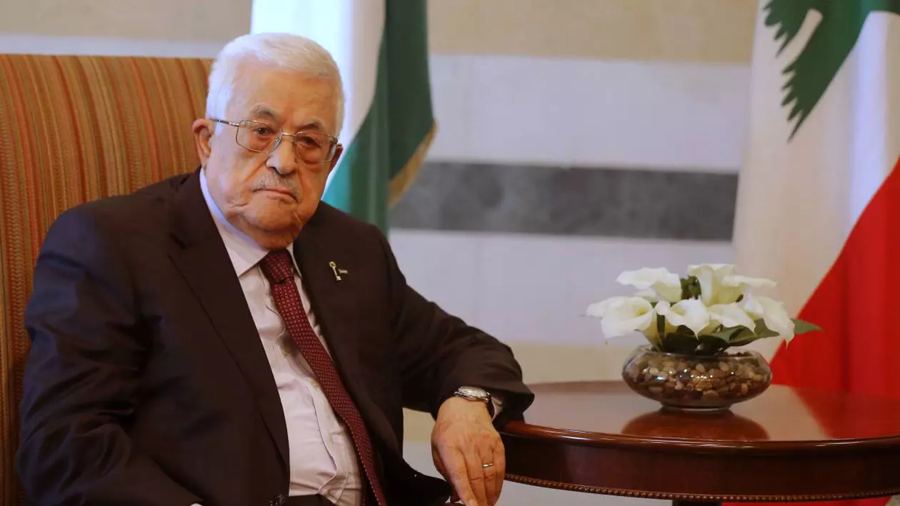 Mahmoud Abbas, președintele Autorității Palestiniene în timp ce stă la masă, îmbrăcat la costum.
