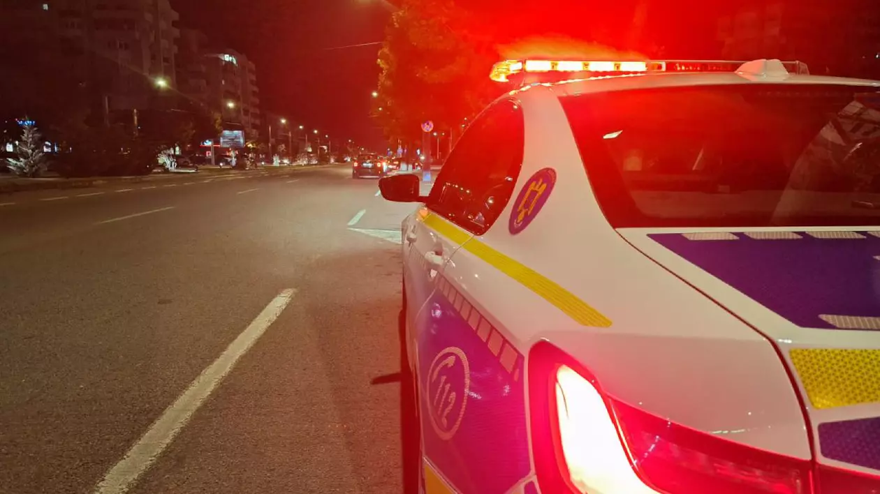 Mașină de Poliție Rutieră, din spate, noaptea, pe un bulevard din București, cu girofarul aprins, cu culoarea roșie
