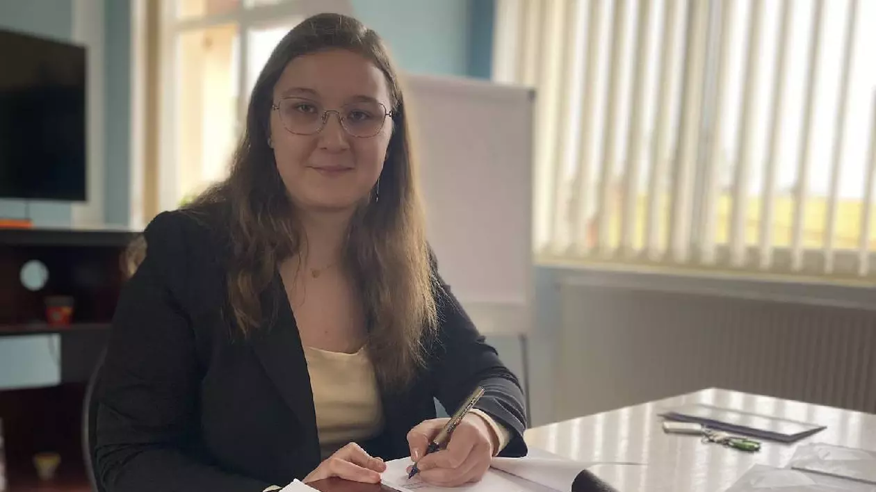 Tânără care stă la birou și scrie