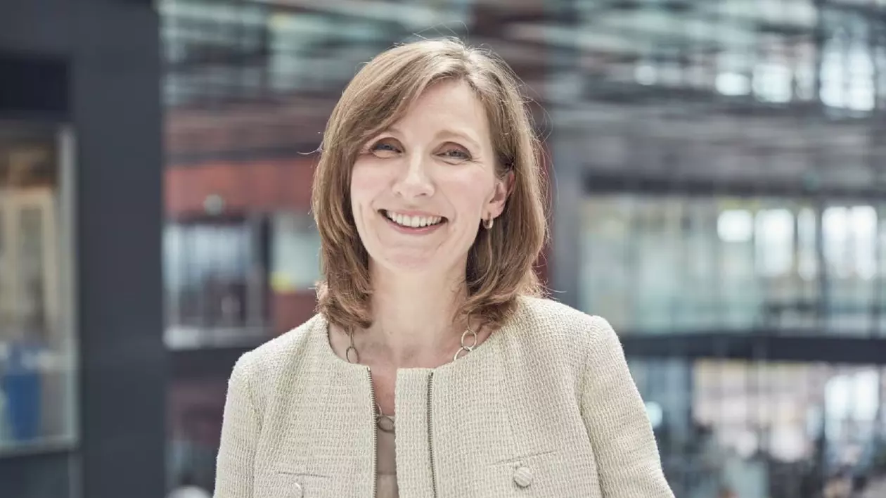 Moira Gilchrist de la PMI, îmbrăcată în bej, în fața unei clădiri cu fațadă de sticlă.