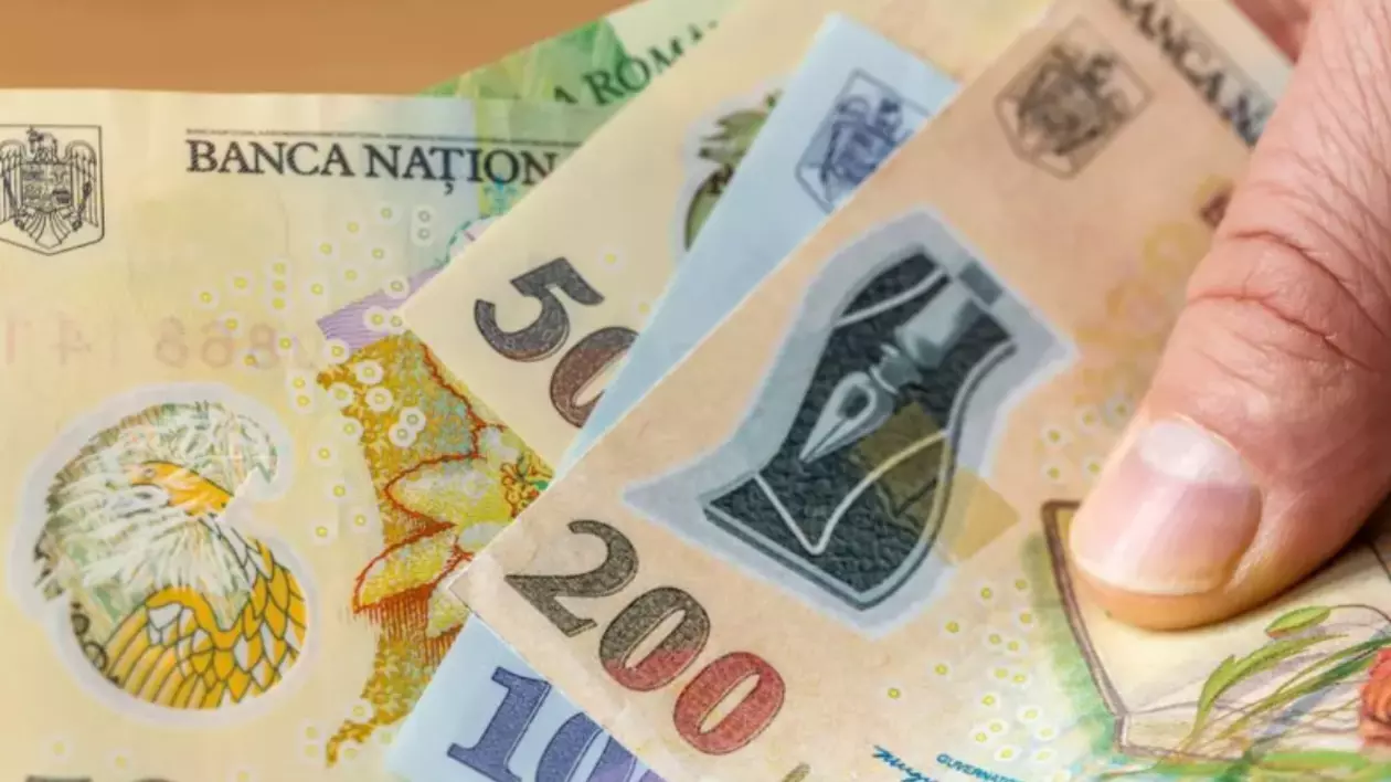 În imagine apar mai multe bancnote ținute de o persoană în mână