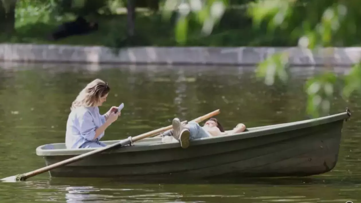 În imagine sunt ilustrate persoane care stau în barcă, pe lac