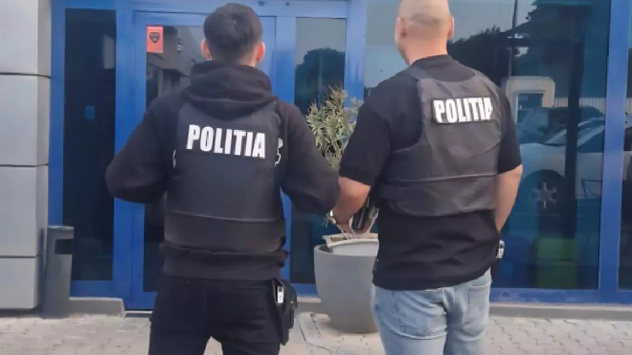 Doi bărbați îmbrăcați cu veste negre pe care scrie Poliția