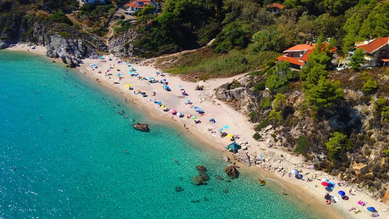 Plajă Grecia, marea albastra, umbrele și turisti intinsi la soare