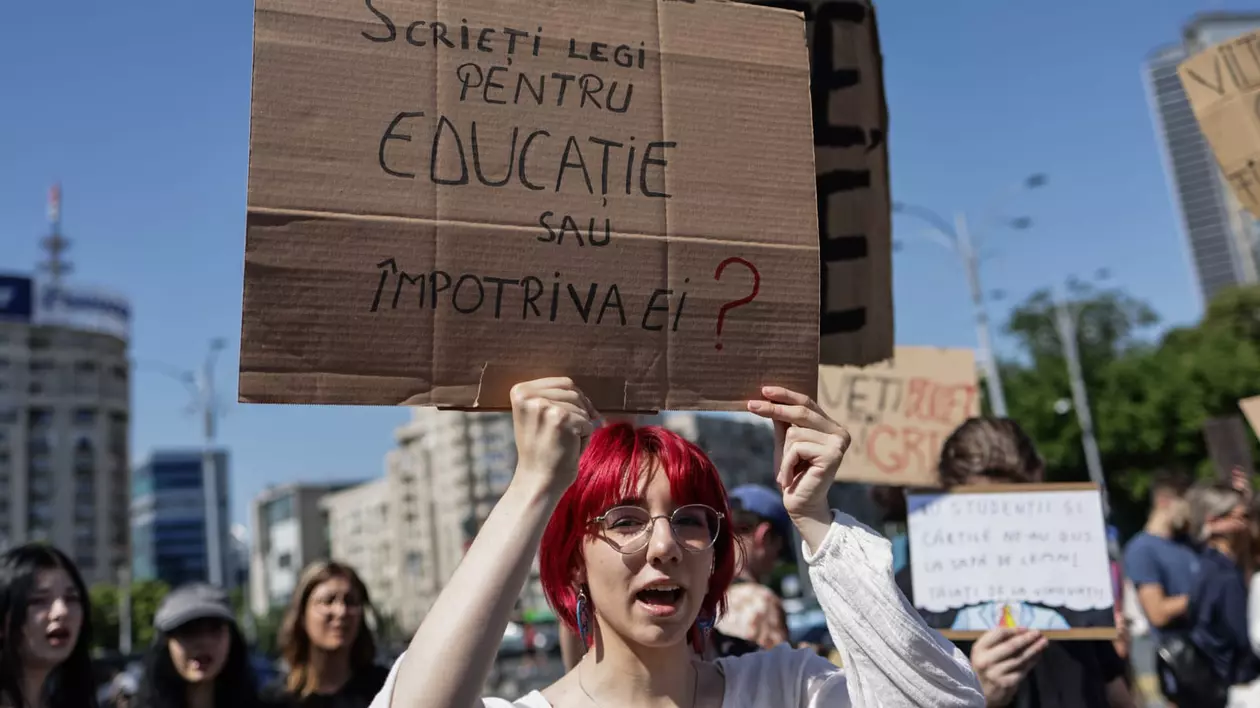 Studentă care protestează în stradă cu o pancartă în mână