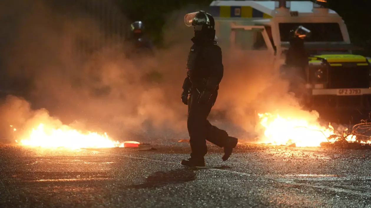Un pompier în echipament de intervenție patrulează pe o stradă în flăcări din Ballymena, Irlanda de Nord