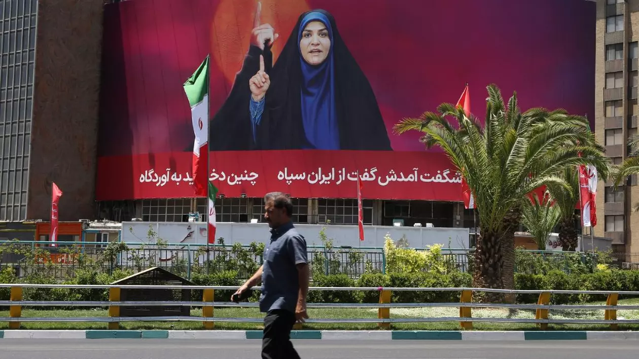 poster imens pe o cladire cu prezentatoarea tv iranina Sahar Emami. prin fata posterului trec eun om