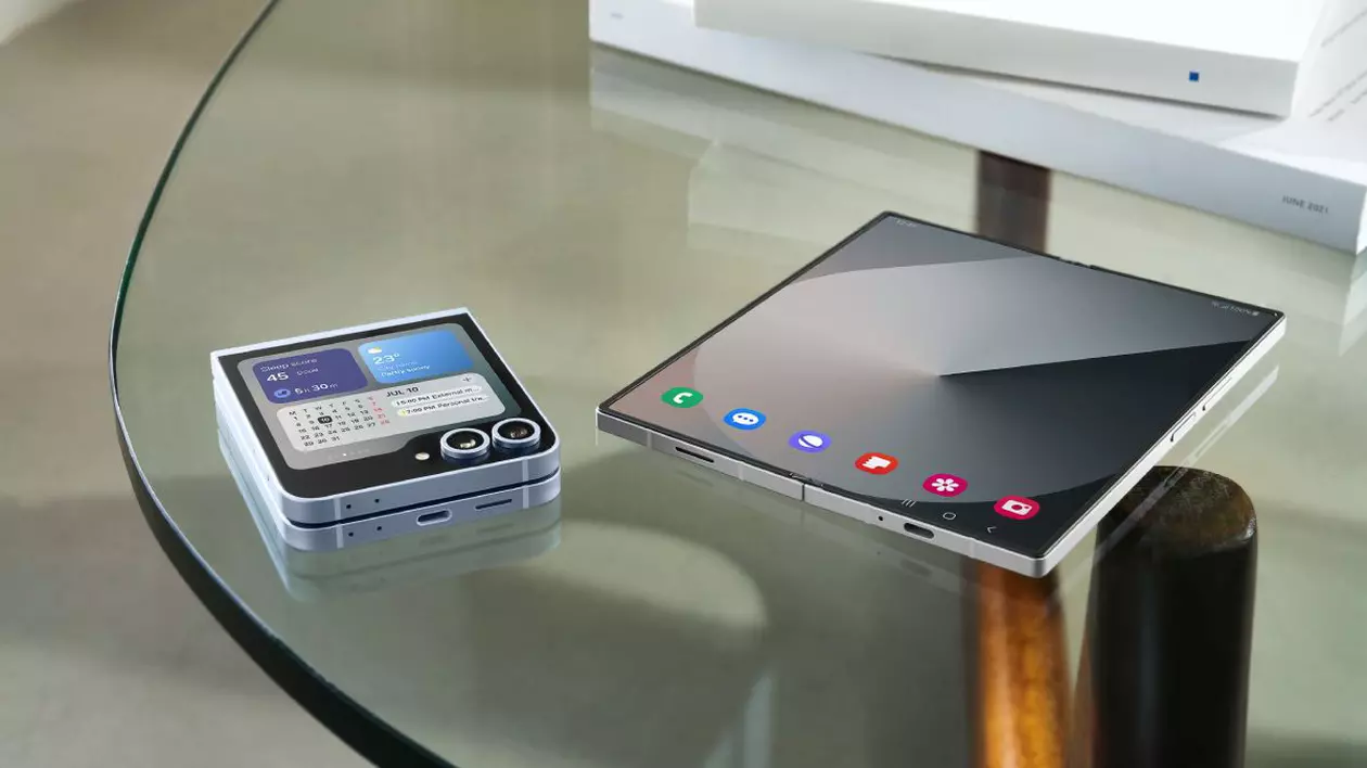 Două telefoane pliabile, Samsung Galaxy Z Fold6 și Z Flip6, așezate pe o masă transparentă lângă două cutii albe.