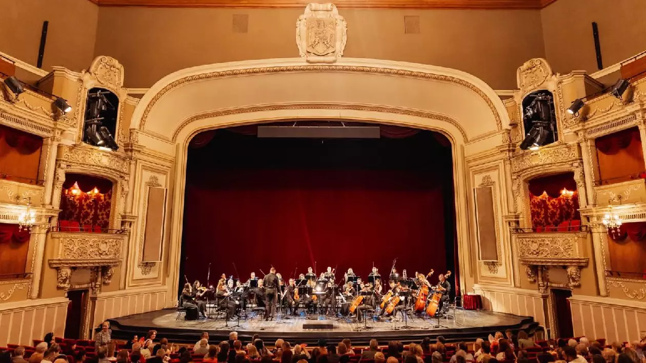 Scena Operei Naționale București, plină de muzicieni, în spate se vede cortina roșie