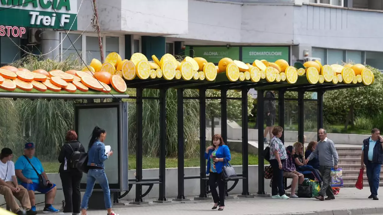Mai mulți oameni așteaptă într-o stație de autobuz decorată cu lămâi și portocale - craiova, iunie 2025