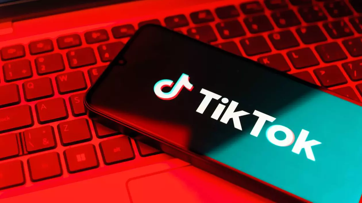 Aplicația TikTok instalată pe un telefon așezat pe tastatura unui laptop.