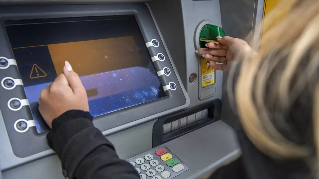 Femeie care introduce cardul într-un ATM pentru o tranzacție