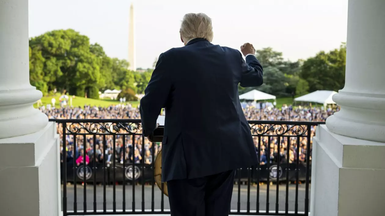 Donald Trump ridică pumnul de pe treptele Casei Albe, văzut din spate.