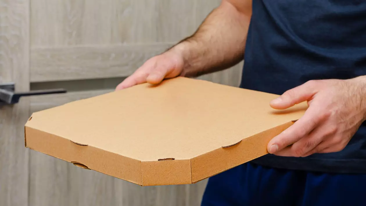 În imagine este ilustrat un bărbat care ține în mână o cutie de pizza