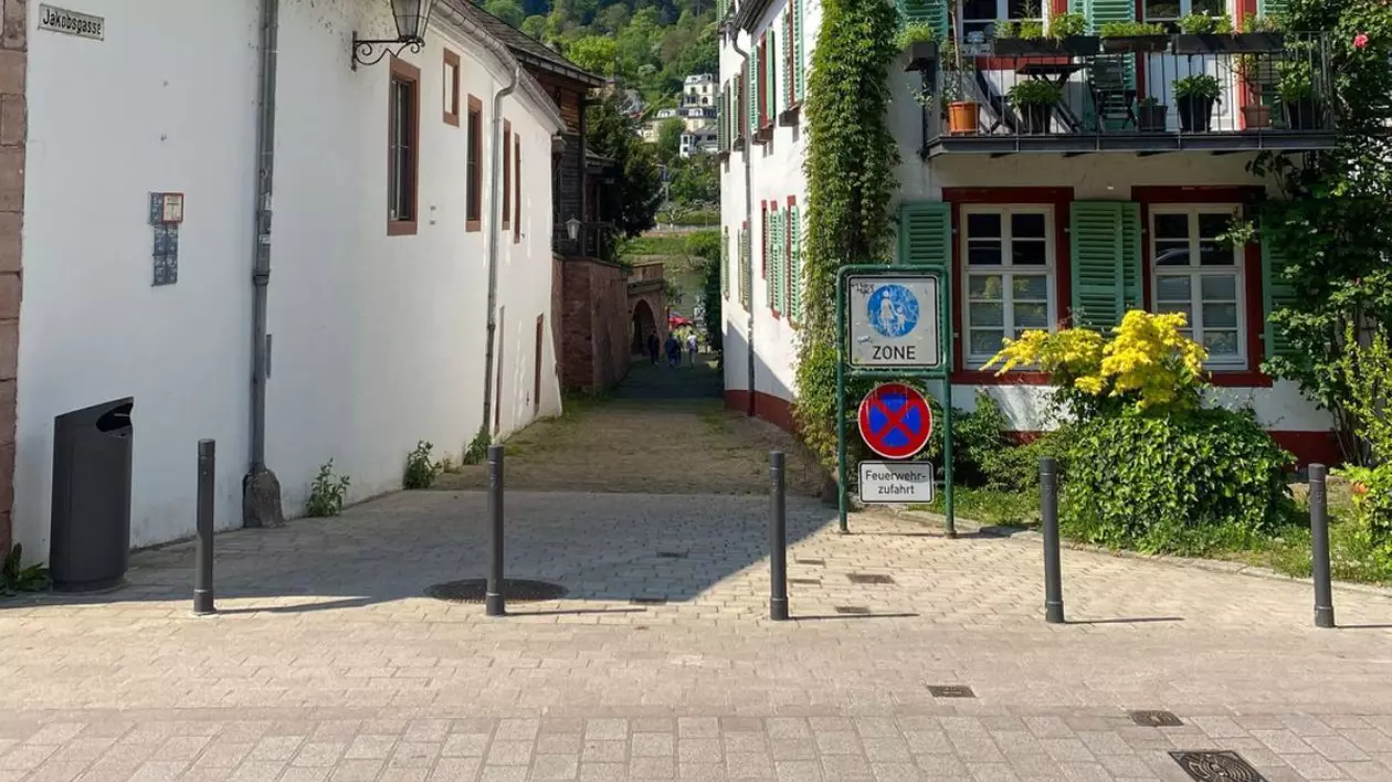Stradă pavată care trece printre două case și duce spre o zonă verde, retrasă, intr-un orășel din Germania,