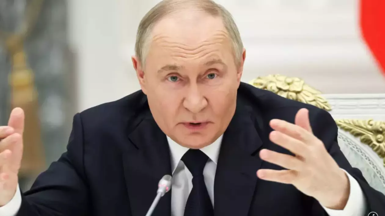 În imagine este ilustrat Vladimir Putin, în costum negru și cămașă albă. Acesta susține un interviu