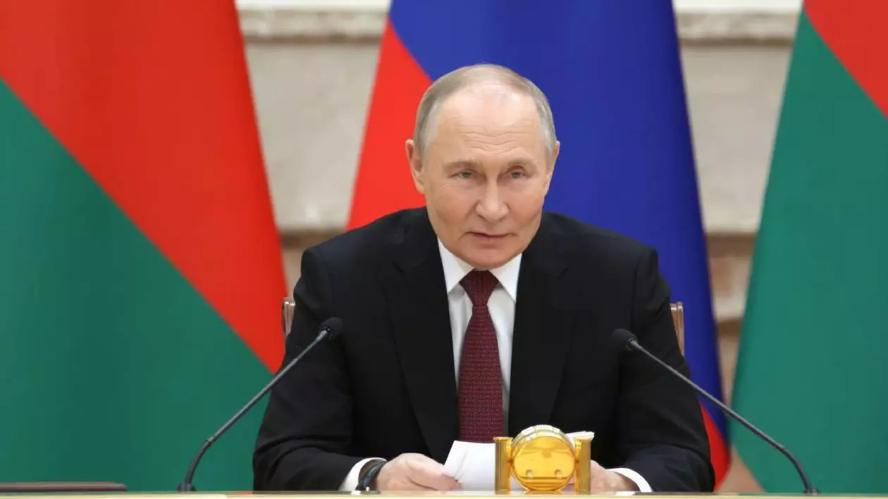 Vladimir Putin în timpul unor declarații, acesta stă la masă și vorbește la microfon, privind fix în direcția camerei.