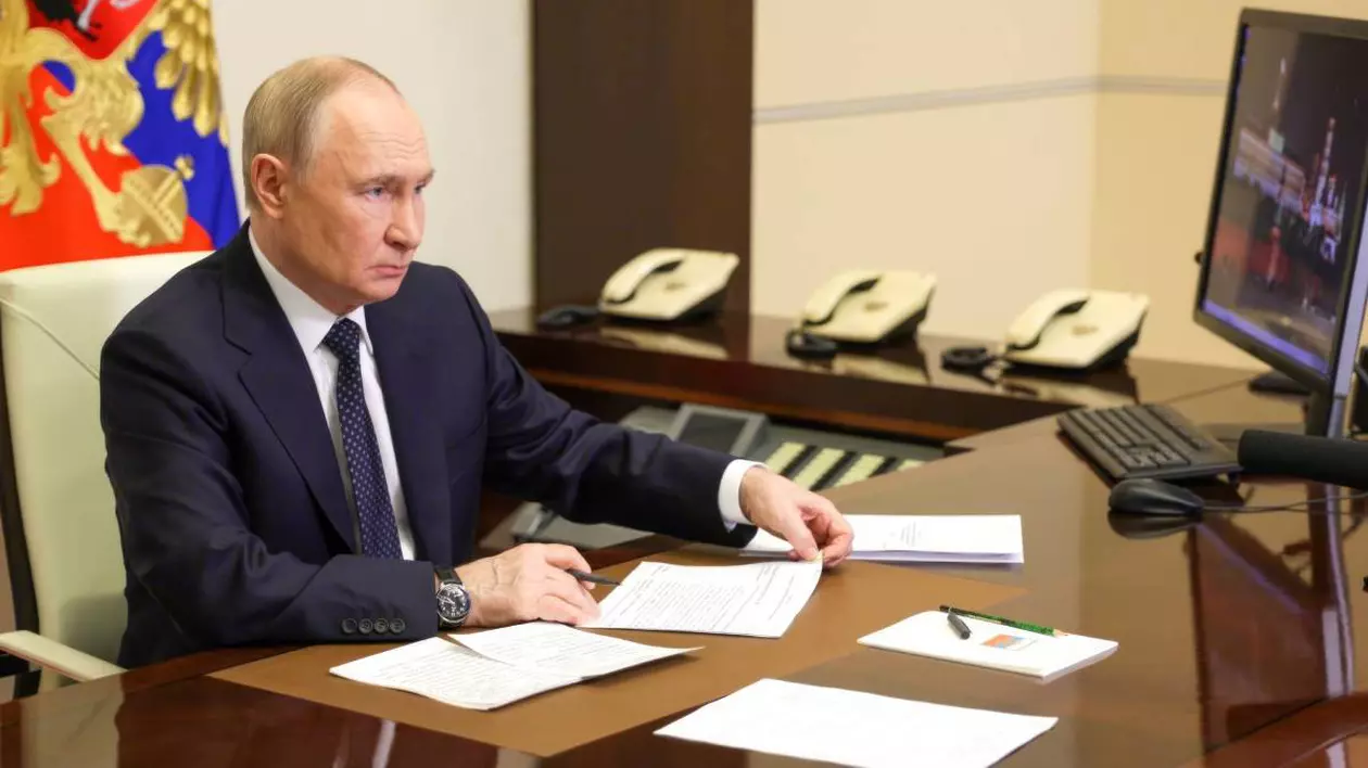 Vladimir Putin în biroul său, stând în fața unui monitor și notând ceva pe o hârtie.